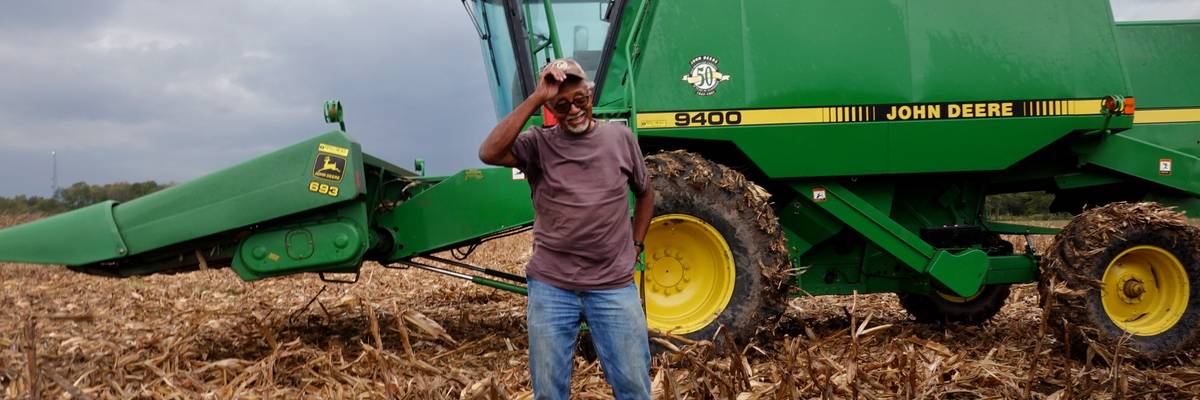 A farmer stands near a harvester