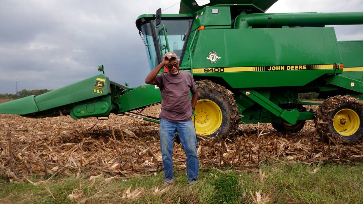 A farmer stands near a harvester