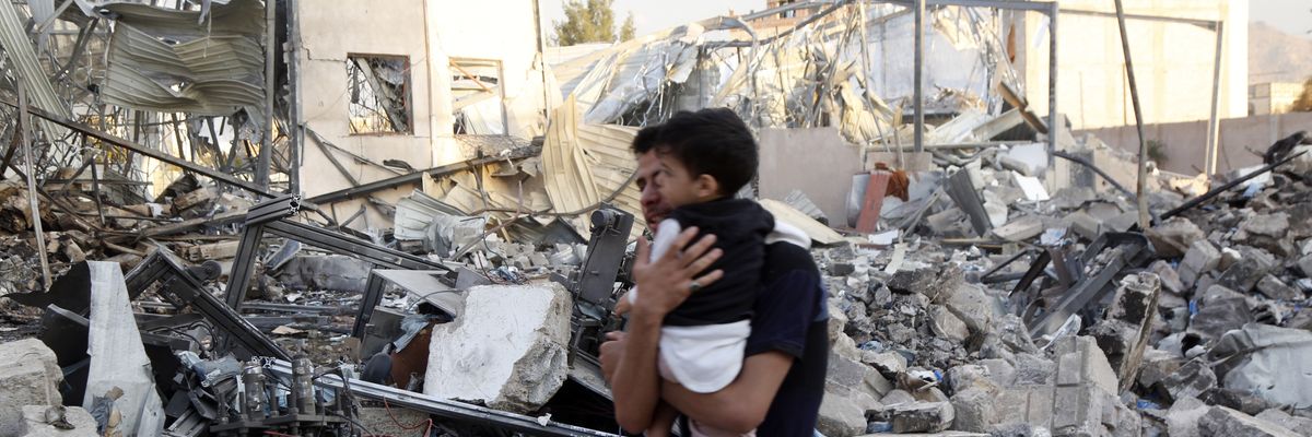 A father and child walk through rubble in Yemen.
