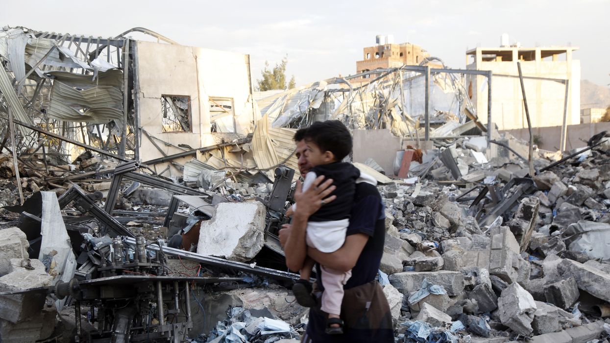 A father and child walk through rubble in Yemen.