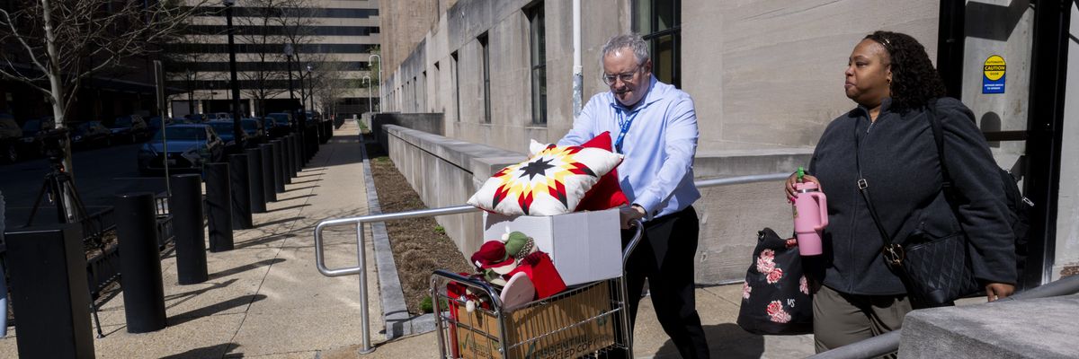 A federal worker (R) who lost her job gets help carrying some of her belongings from her office