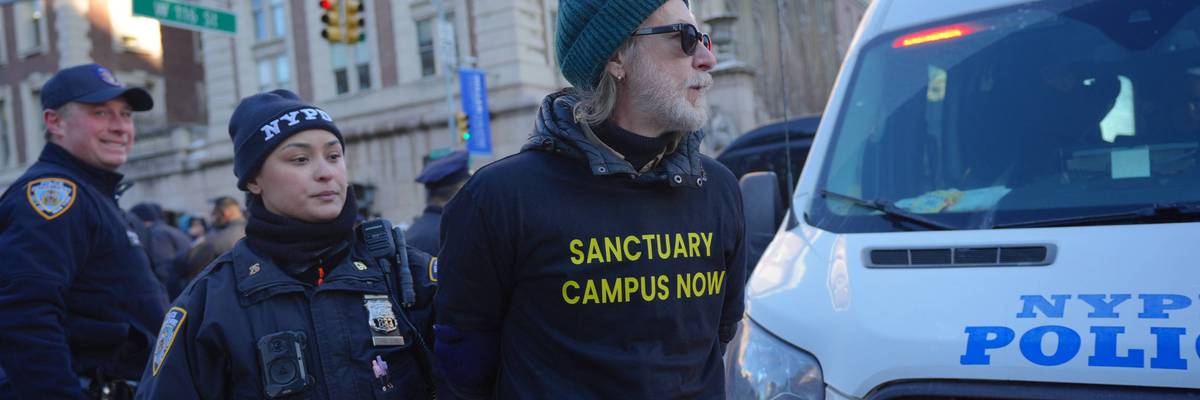 A female NYPD officer arrests an activist in a shirt reading "Sanctuary Campus Now"