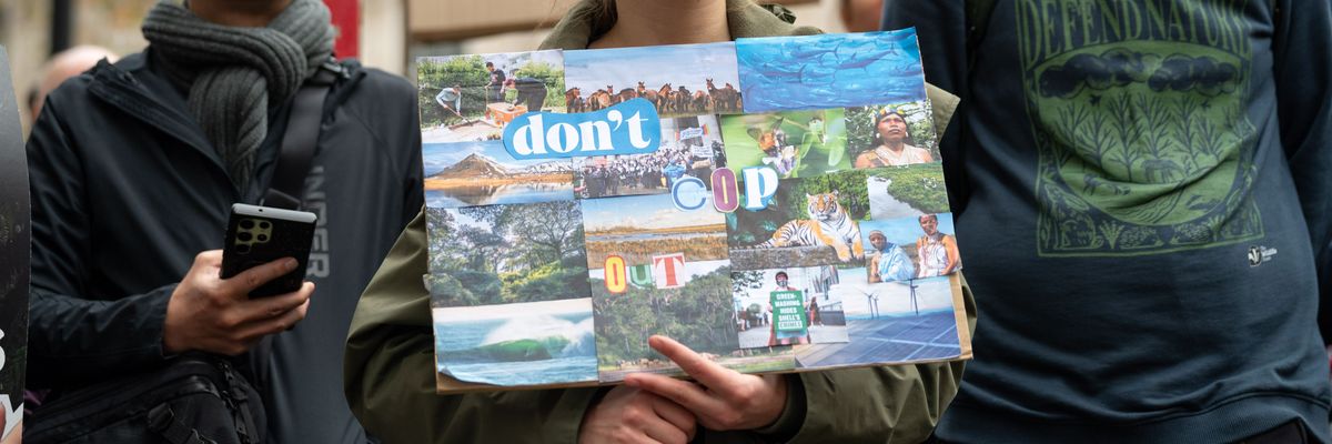 A female protester holds a placard saying "Don't COP out"