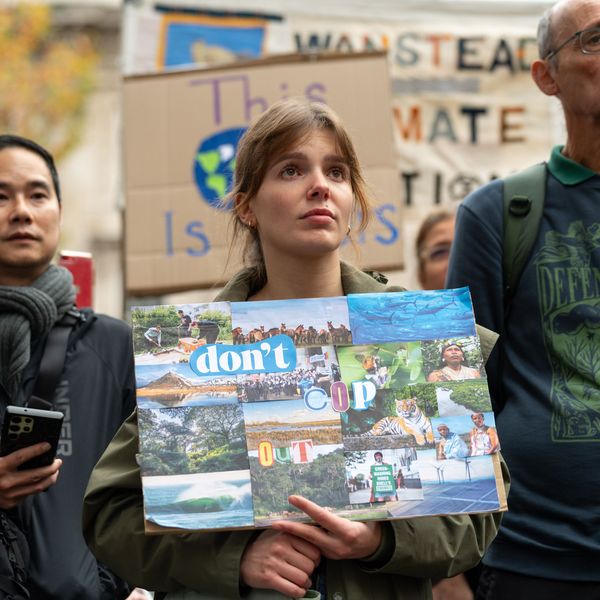 A female protester holds a placard saying "Don't COP out"