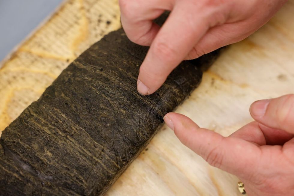 A finger points to a line in a sediment.