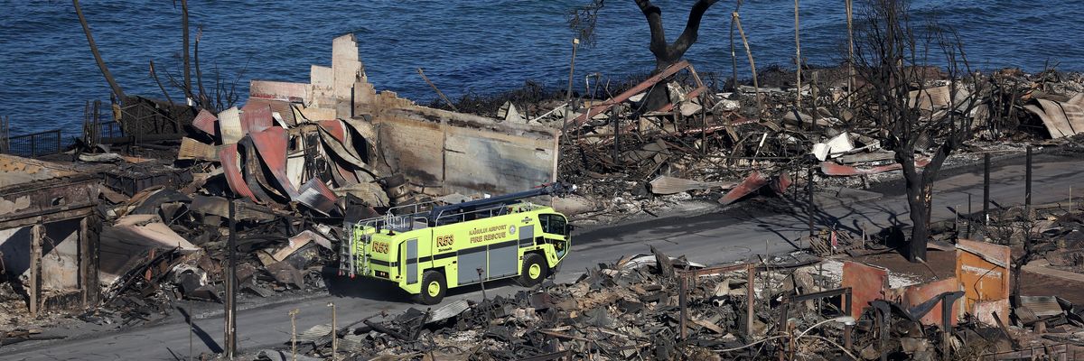 A fire truck drives through a destroyed Lahaina neighborhood.