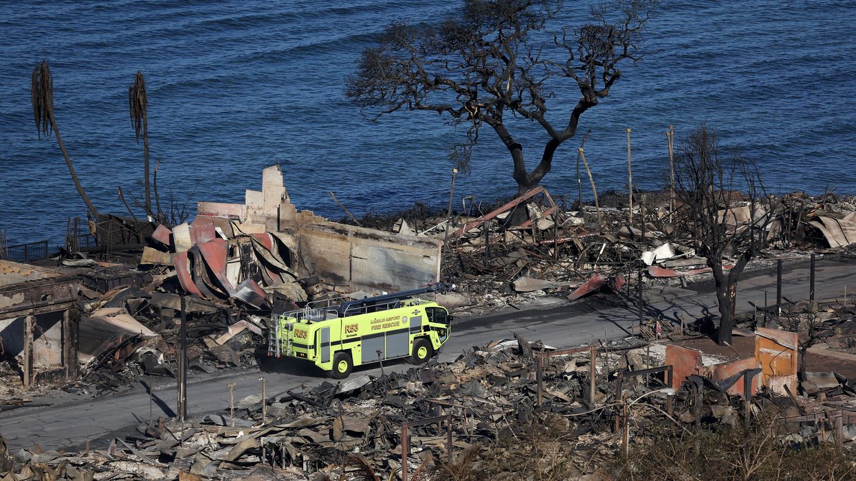 A fire truck drives through a destroyed Lahaina neighborhood.
