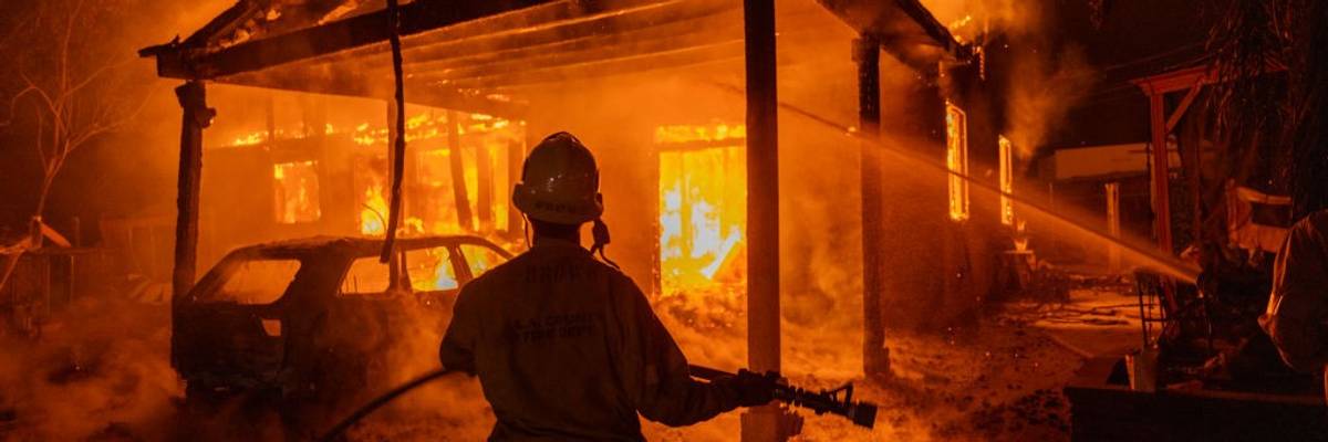 A firefighter faces a burning house in Los Angeles