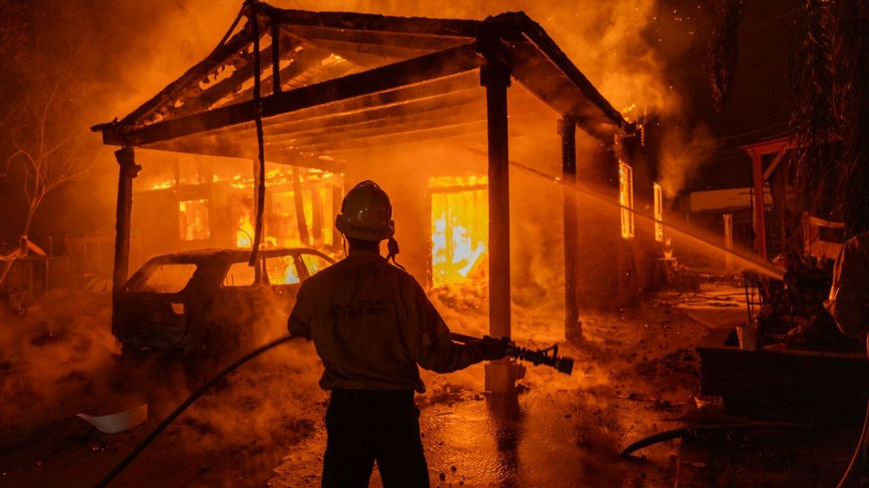 A firefighter faces a burning house in Los Angeles
