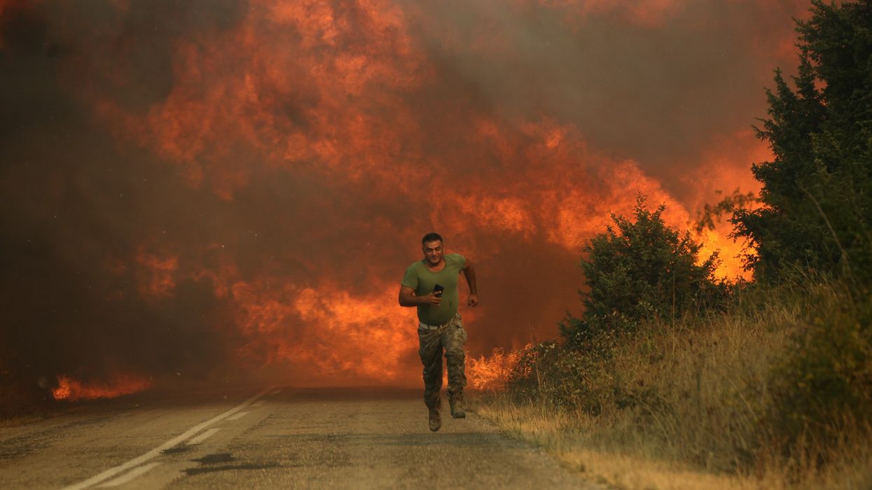 A firefighter runs as a wildfire intensifies
