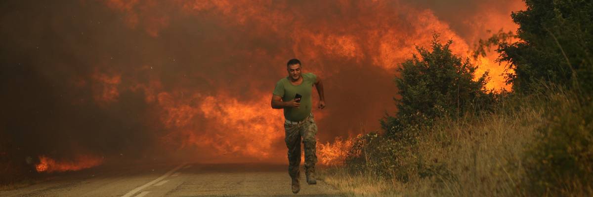 A firefighter runs from flames in Greece.