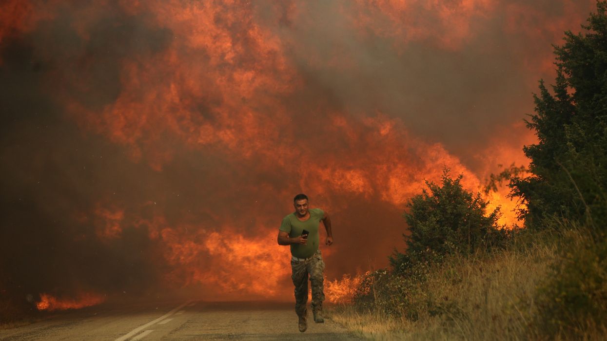 A firefighter runs from flames in Greece.