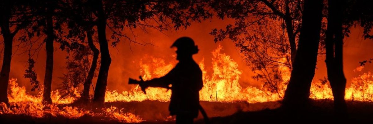 A firefighter stands in front of flames