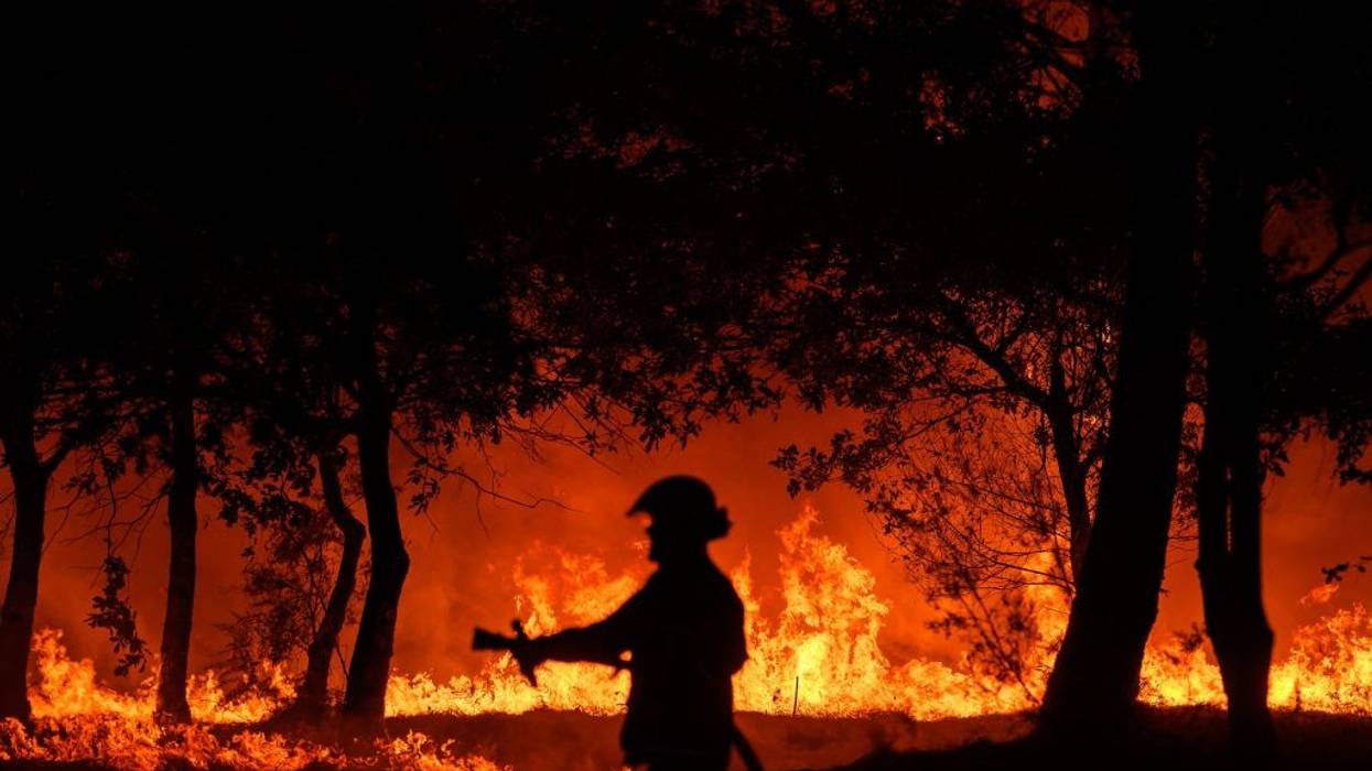 A firefighter stands in front of flames