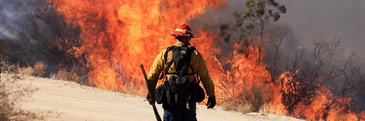 A firefighter walks toward flames as the Highland Fire burns