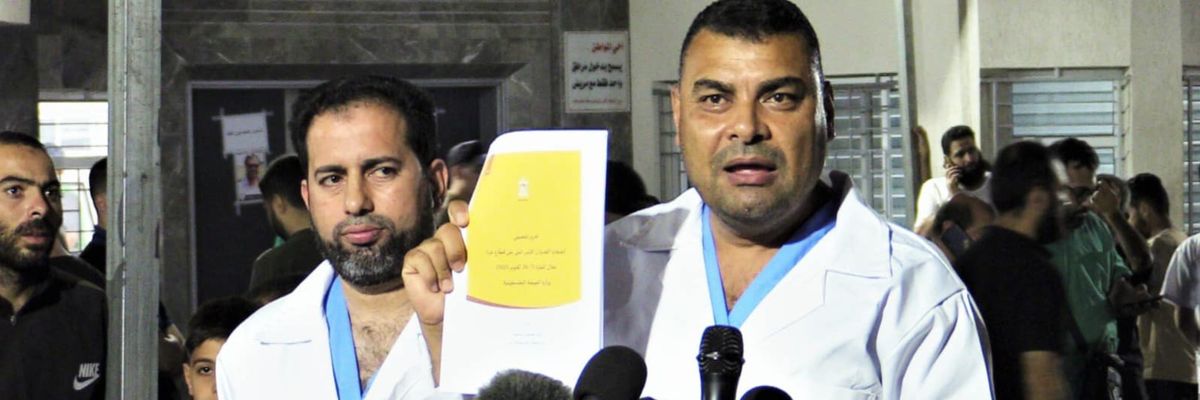 A Gaza health official in a white medical coat holds a list of the 6,747 people killed by Israeli bombing and shelling. 