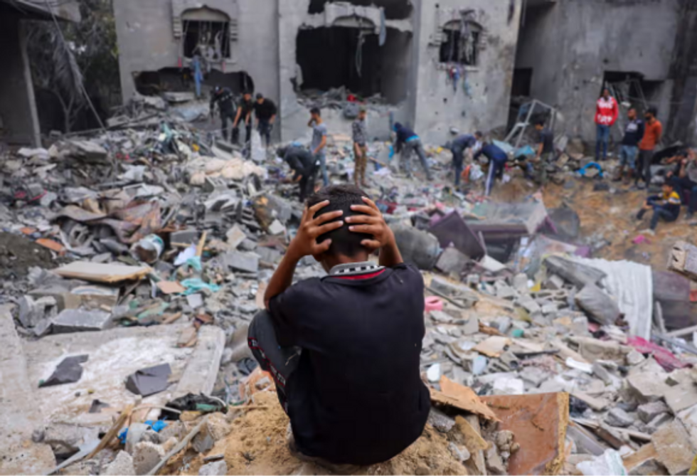 A Gazan child watches as people sort through rubble after an Israeli airstrike on Rafah. 