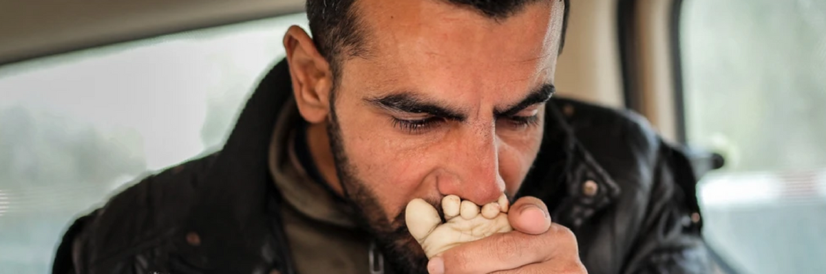 A Gazan man kisses the foot of his dead baby, killed in an Israeli strike 