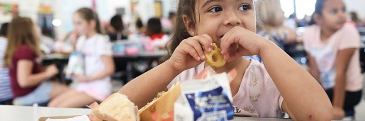 A girl eats a smiley face fry during her lunch period