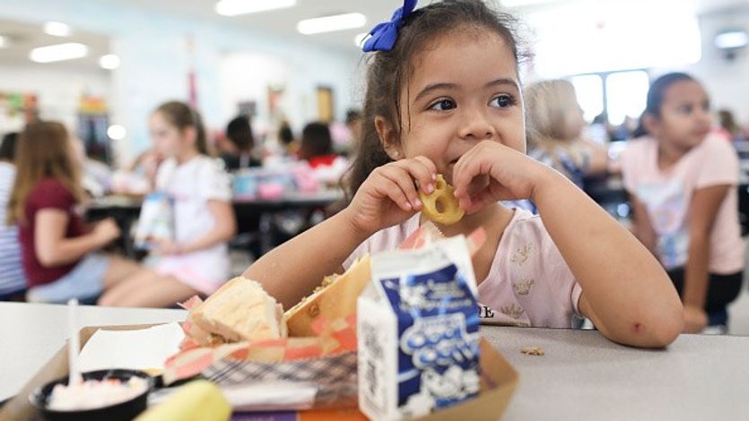 A girl eats a smiley face fry during her lunch period