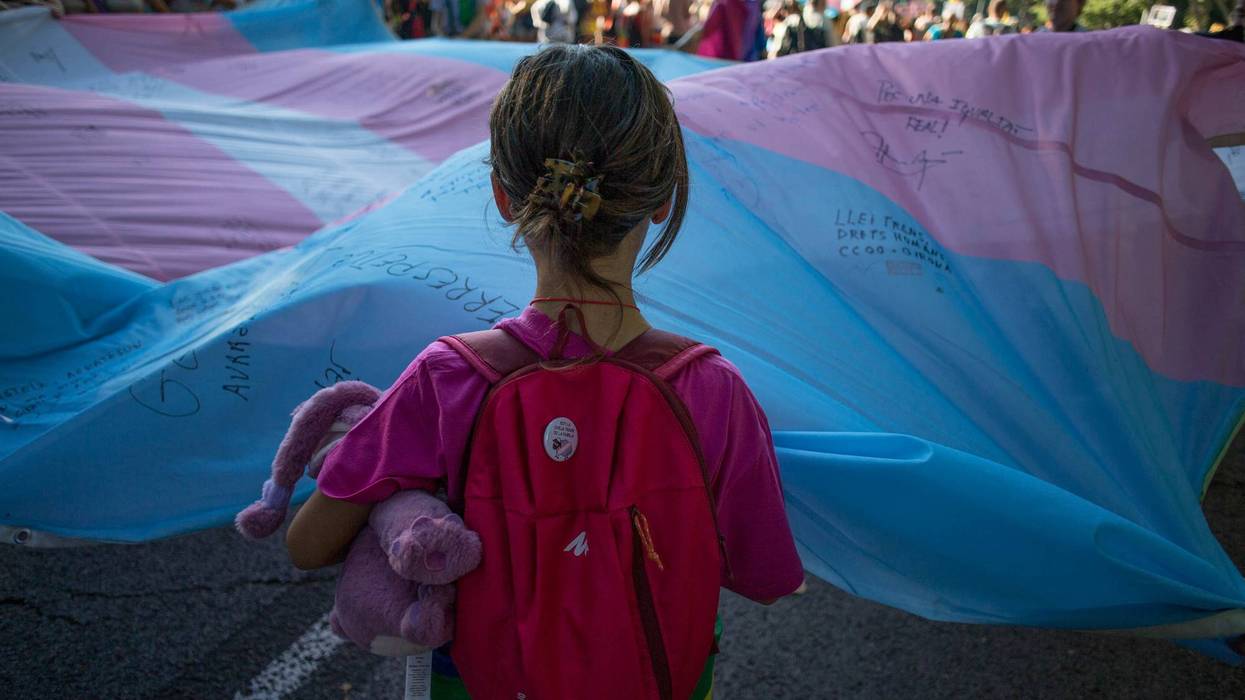 A girl helps hold a large transgender flag