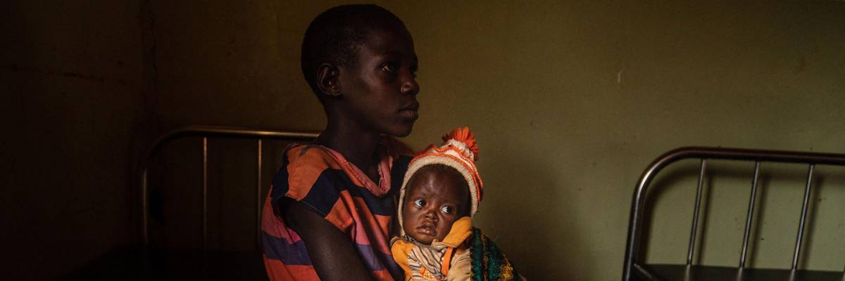 A girl holds her malnourished sister