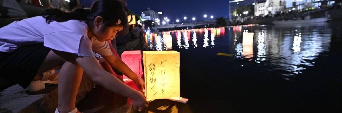 A girl places a lantern in a river to commemorate the Hiroshima bombing
