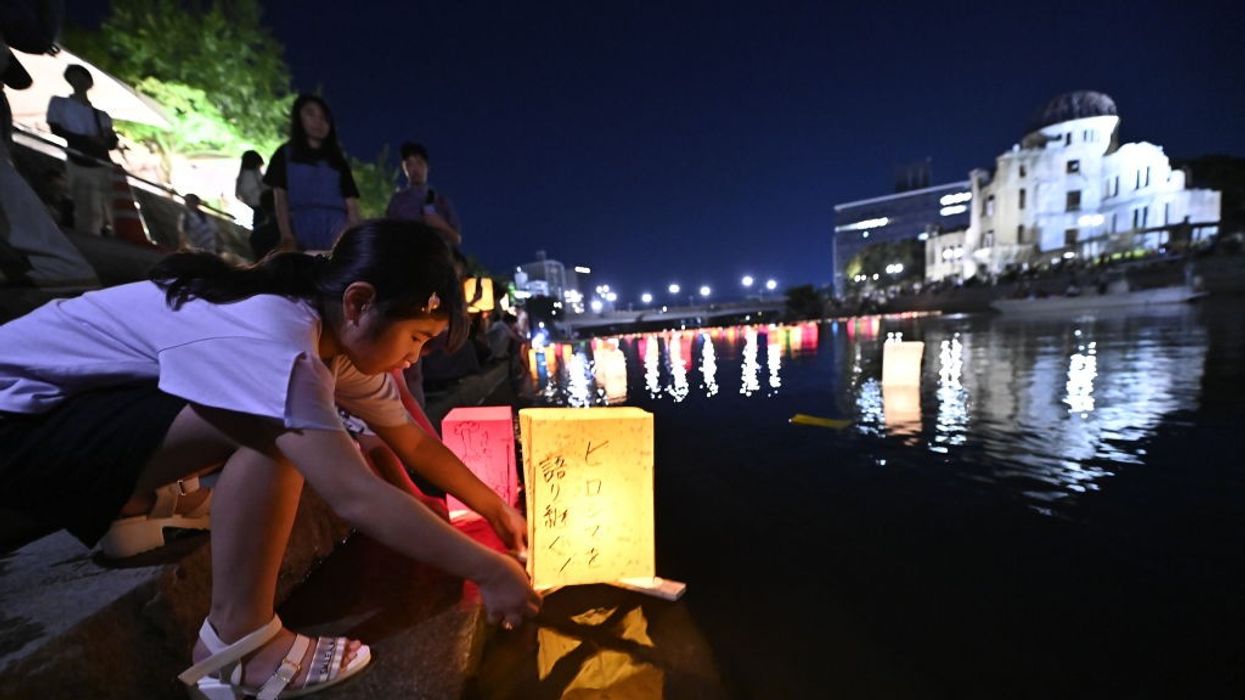A girl places a lantern in a river to commemorate the Hiroshima bombing