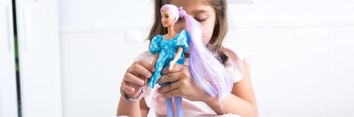 A girl plays with a Barbie.