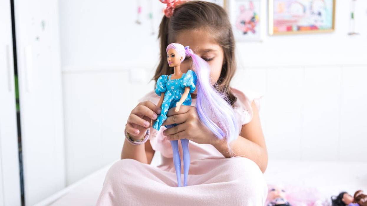 A girl plays with a Barbie.