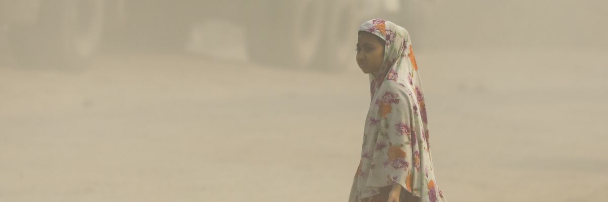 A girl walks on a heavily polluted road