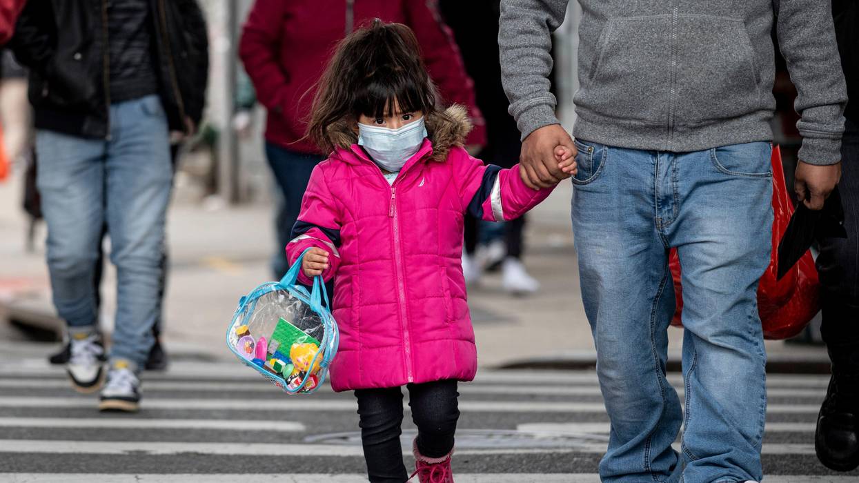 A girl, wearing a mask, walks down a street in the Corona neighborhood of Queens on April 14, 2020 in New York City.