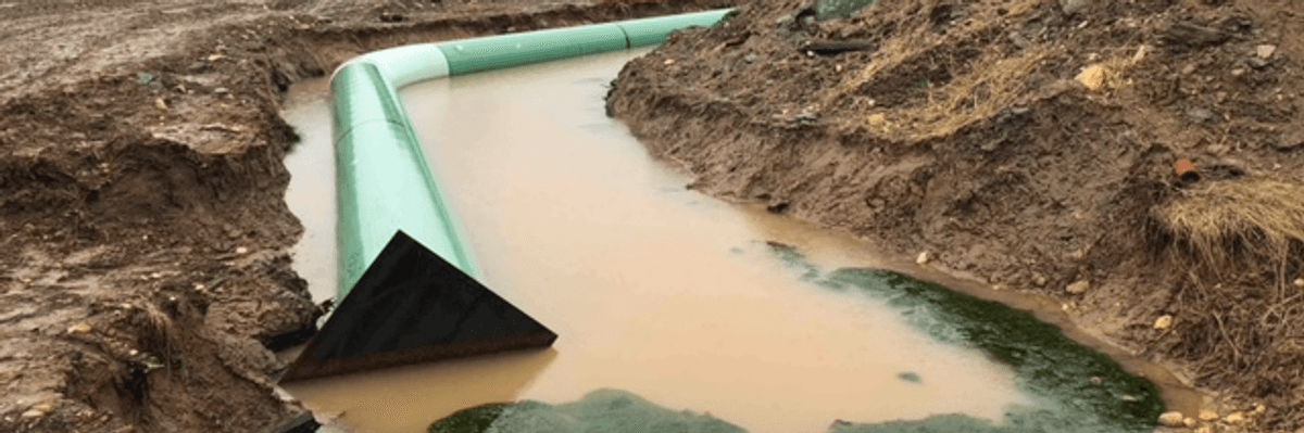A green pipeline piece in brown water.