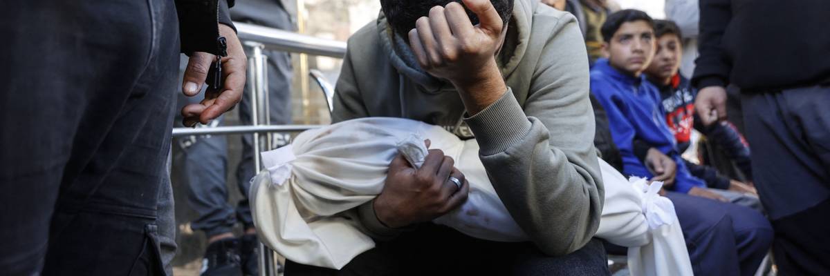 A grieving Palestinian man carries the shrouded body of his 4-month-old brother, who was killed in an IDF strike