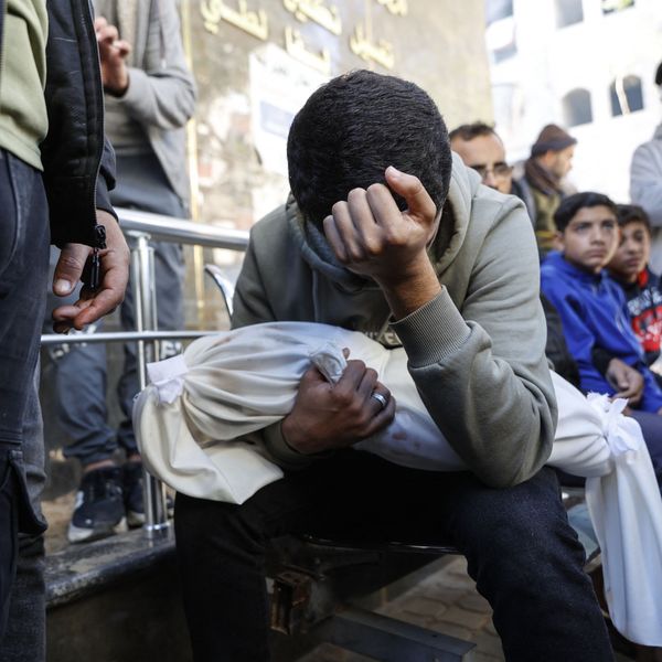 A grieving Palestinian man carries the shrouded body of his 4-month-old brother, who was killed in an IDF strike