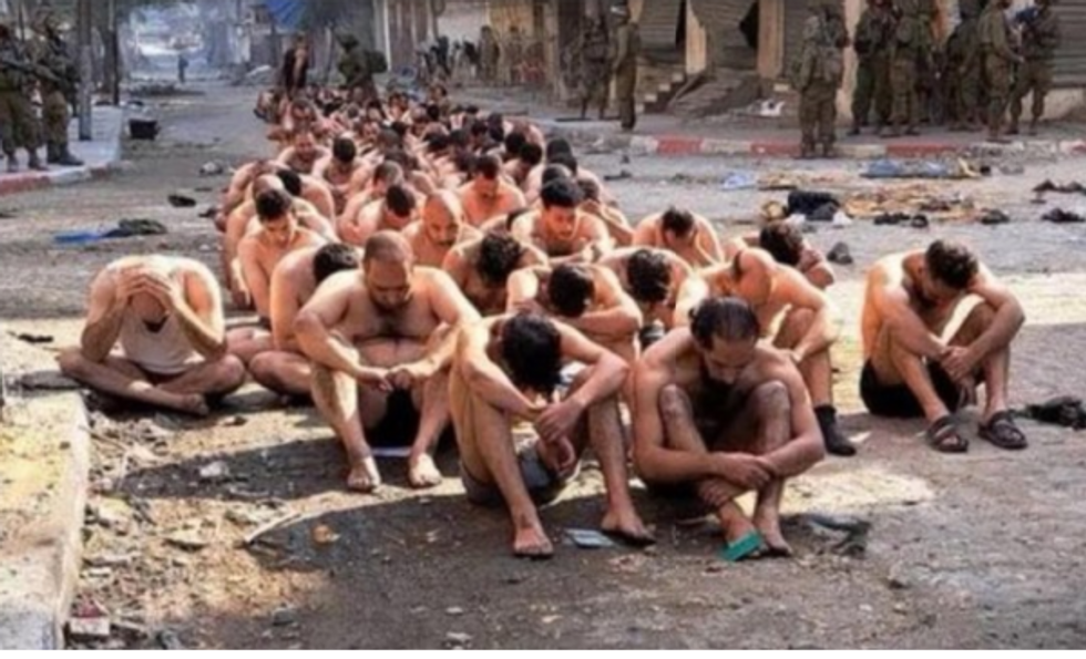 A group of Palestinian men from Beit Lahia, stripped and detained by Israeli military, sit in the street