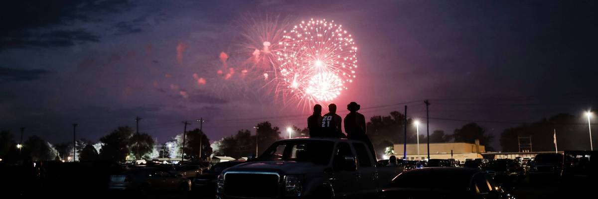 A group of people on a car at night with fireworks in the sky