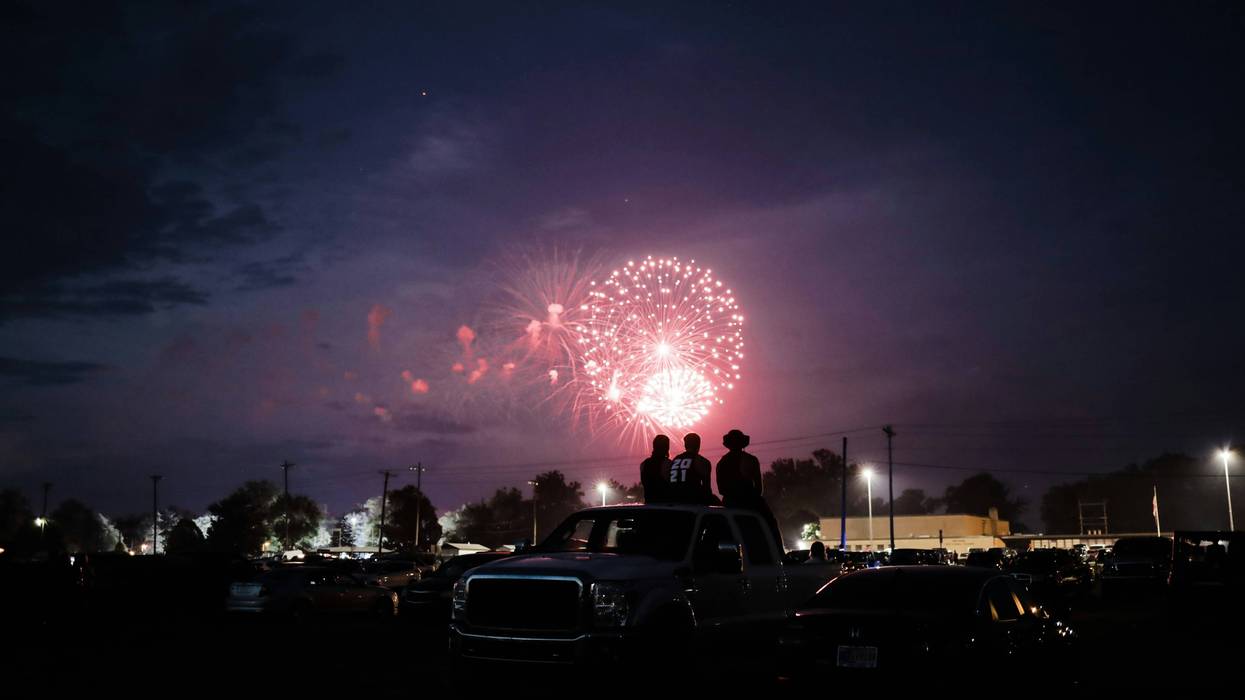 A group of people on a car at night with fireworks in the sky