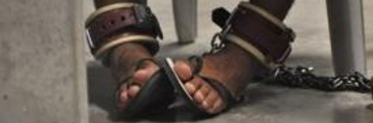 A Guantanamo detainee's feet are shackled to the floor