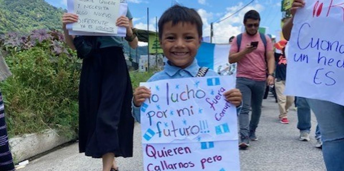 A Guatemalan child holds up a sign reading, "I am fighting for my future," in Spanish.
