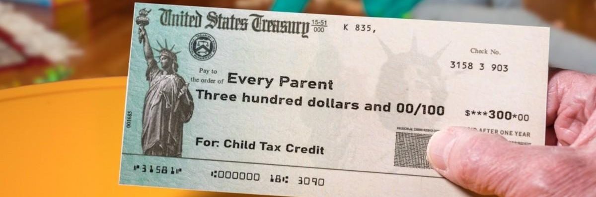 A hand holds a check for a child tax credit. 