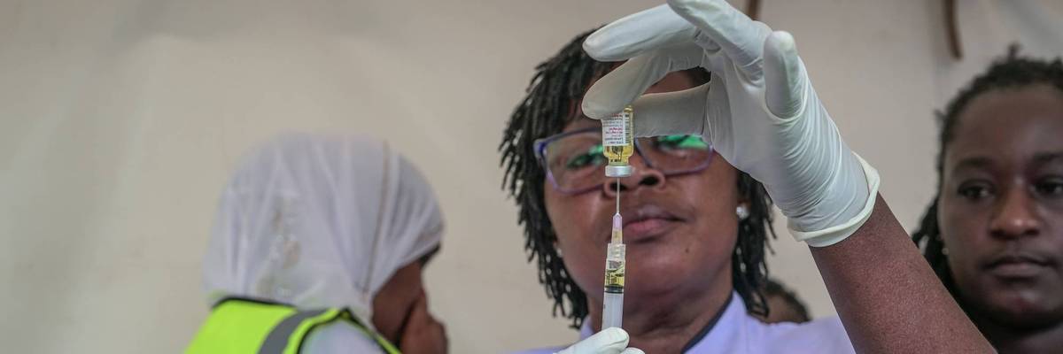 A healthcare worker fills a syringe with a dose of