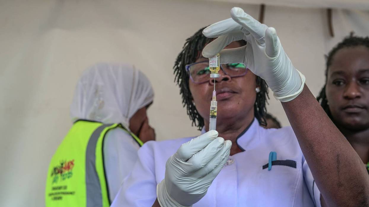 A healthcare worker fills a syringe with a dose of