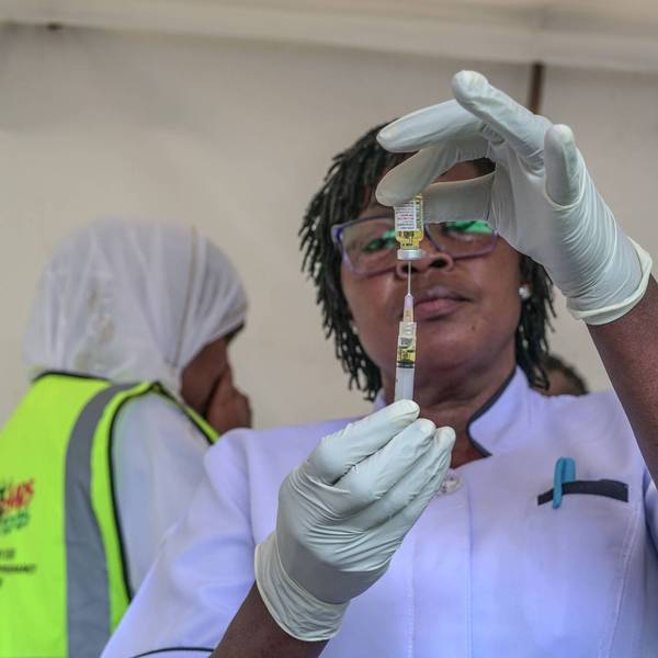 A healthcare worker fills a syringe with a dose of