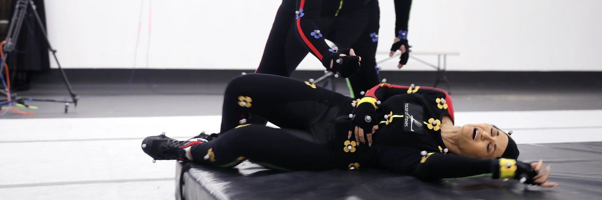 A journalist and video game actor demonstrate motion-capture acting.