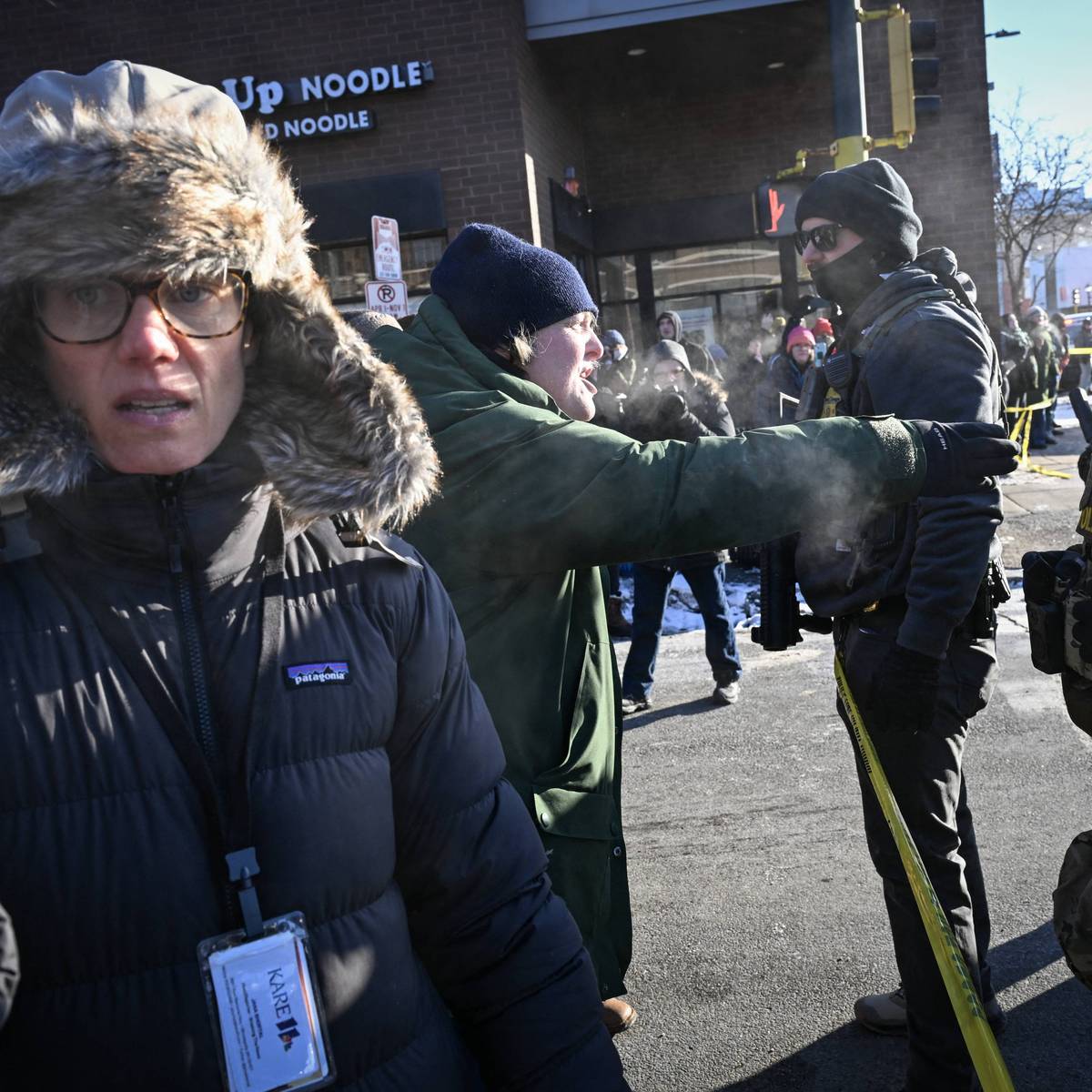 A journalist (L) records on her phone as a demonstrator shouts