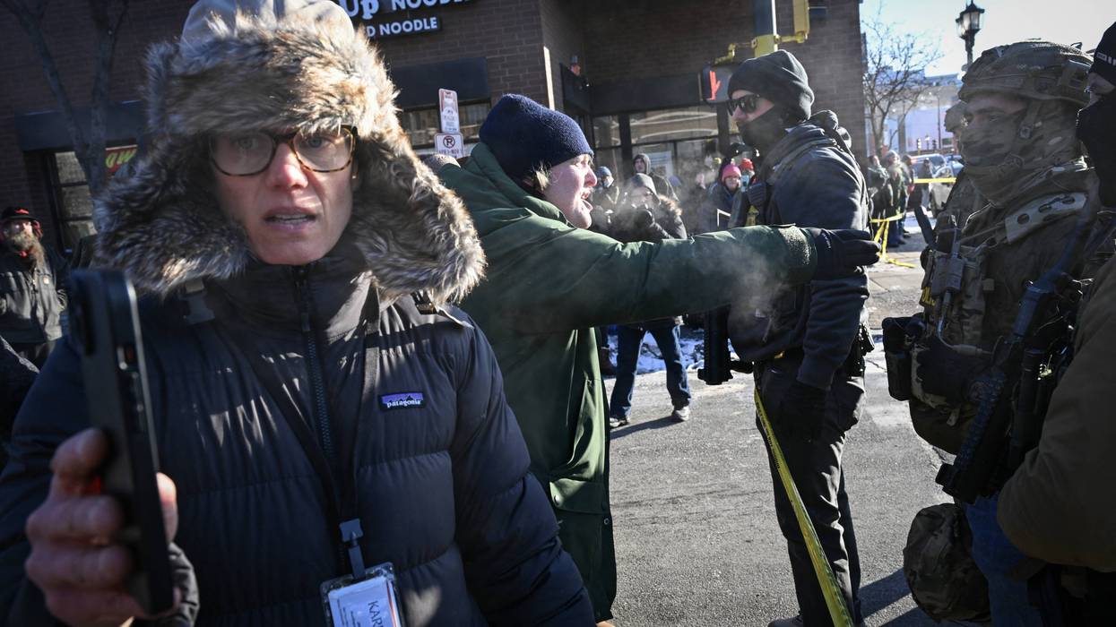 A journalist (L) records on her phone as a demonstrator shouts