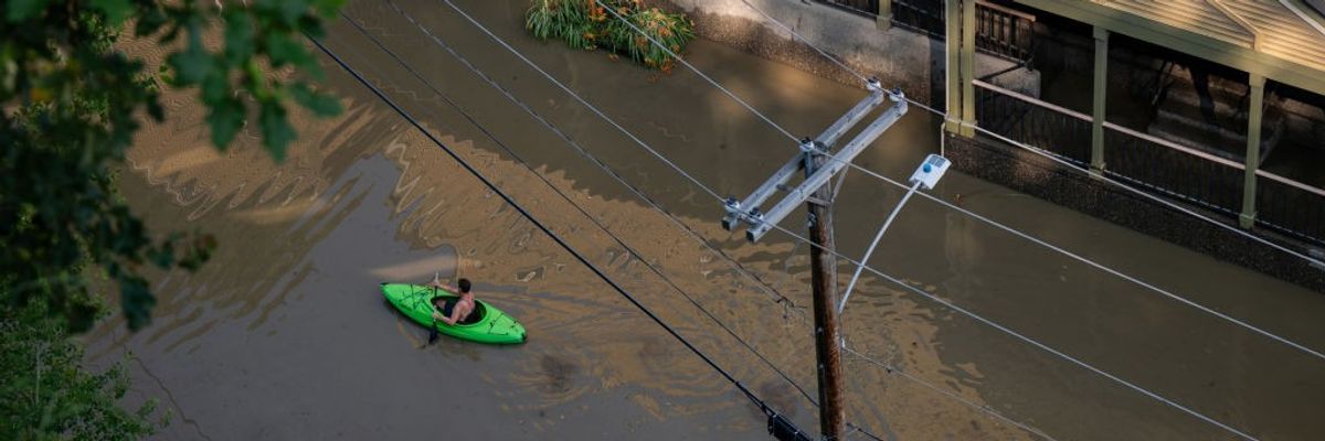 A kayaker paddles down a flooded street.