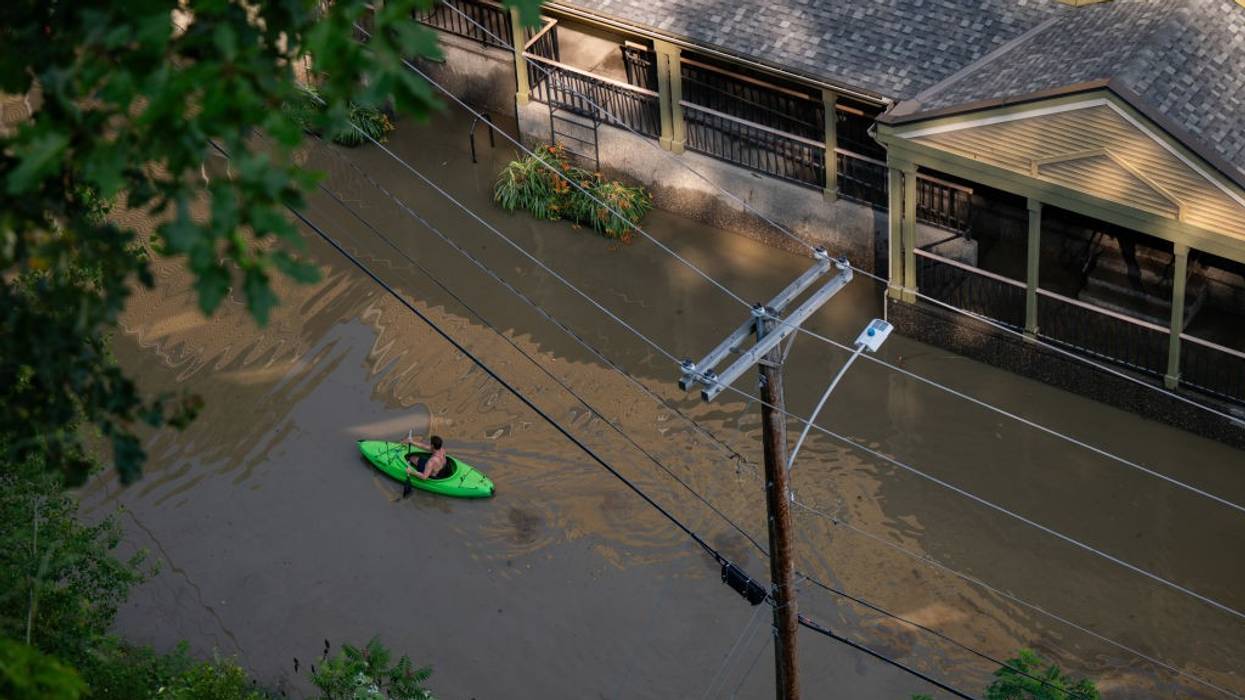 A kayaker paddles down a flooded street.