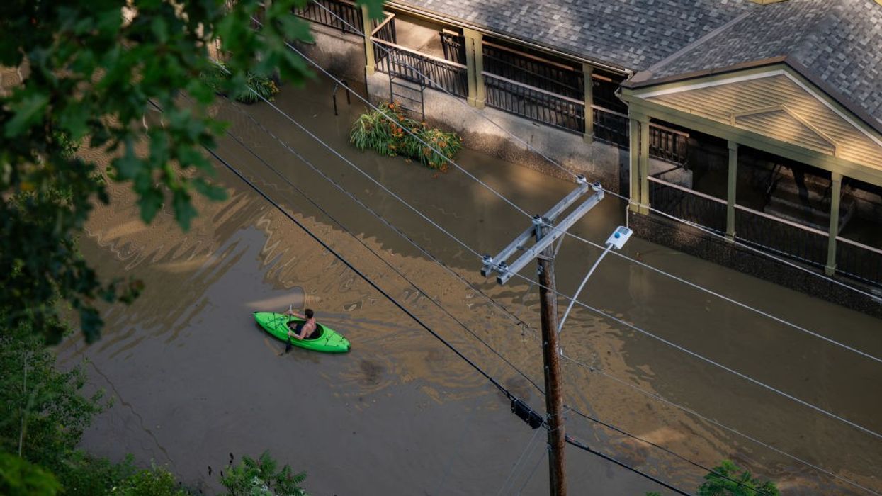 A kayaker paddles down a flooded street.